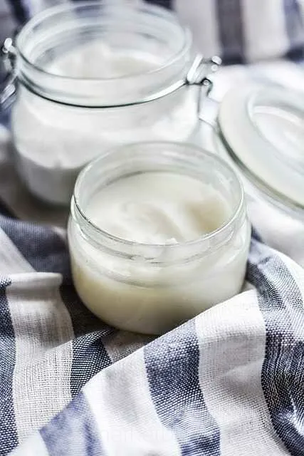 Słoik z olejem kokosowym obok świeżego kokosa – produkt o wszechstronnym zastosowaniu