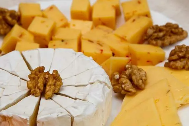 Żółty ser w plasterkach ułożony na desce – klasyczny produkt nabiałowy do kanapek i przekąsek